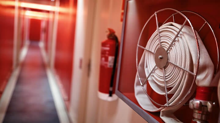 Fire extinguisher and fire hose on wall in hotel hallway